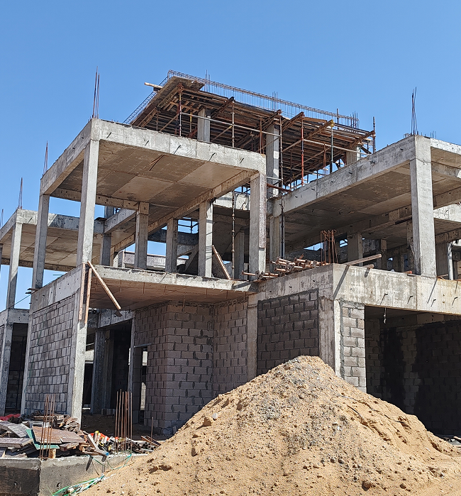 A large concrete building under construction, showcasing scaffolding and construction equipment surrounding the site.