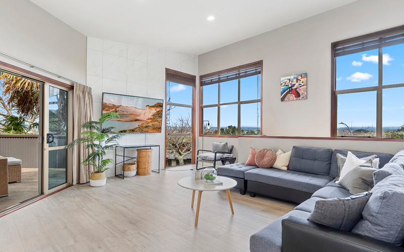 A cozy living room featuring a couch, a television, and a large window showcasing a beautiful ocean view.