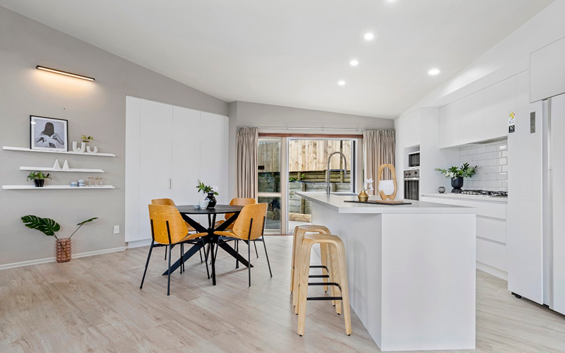 A modern kitchen featuring white cabinets and warm wooden floors, creating a bright and inviting atmosphere.