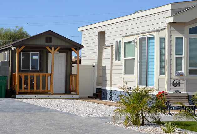 A small house featuring a welcoming porch, surrounded by greenery and a clear blue sky.